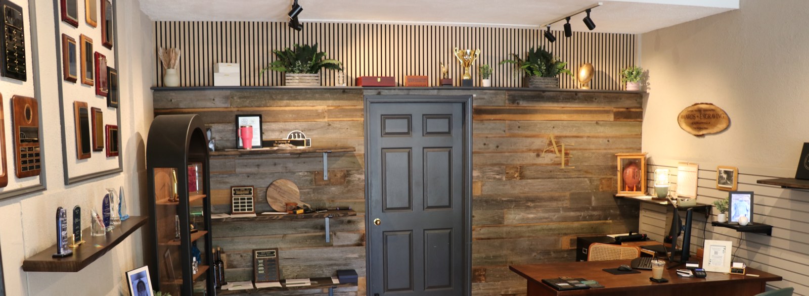 The Awards & Engraving showroom on Milwaukee Avenue — plaques, trophies and awards on the walls and the reclaimed-wood feature wall