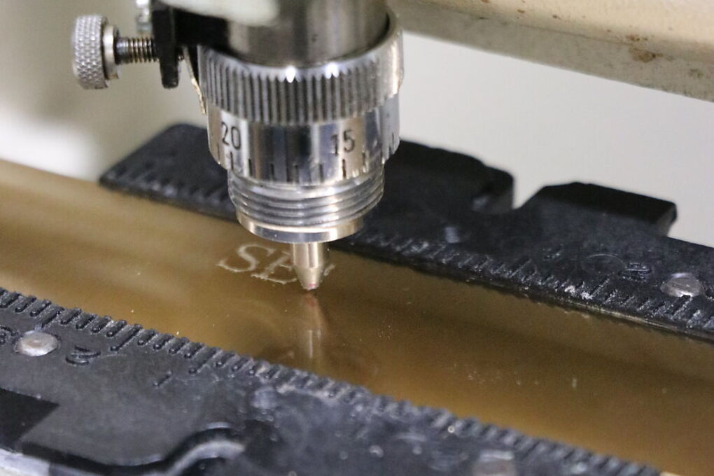 Close-up of a diamond drag tip burnishing a line into brass